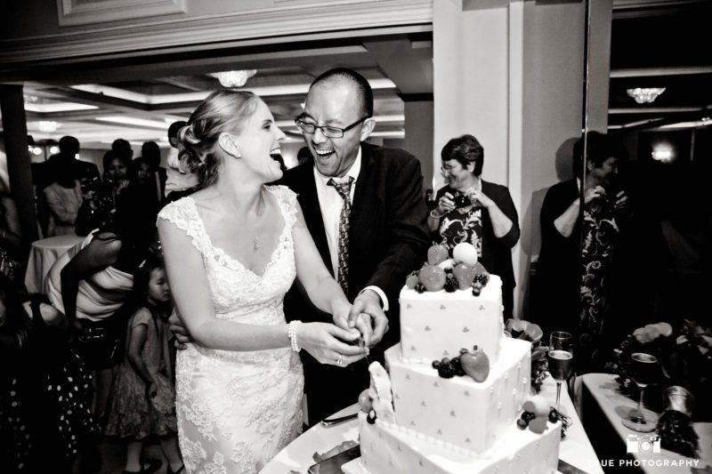 Wedding couple laughing over cake cutting