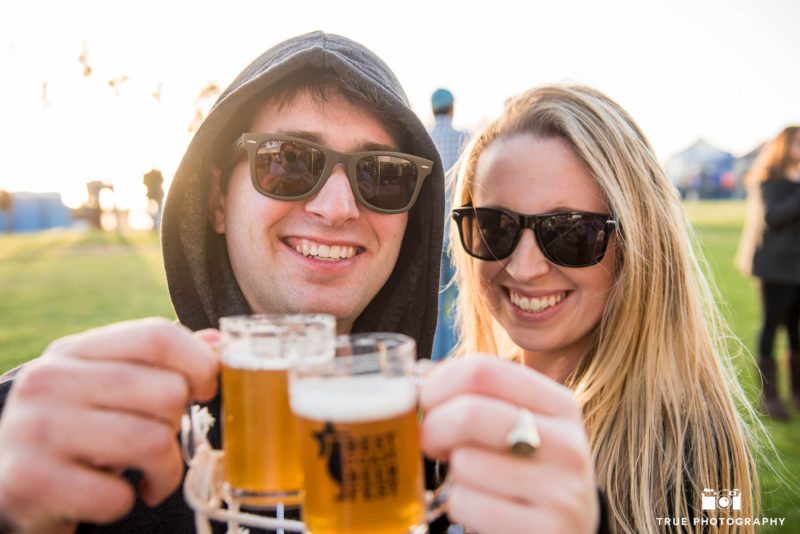 Young couple toasts beer glasses at Best Coast Beer Fest