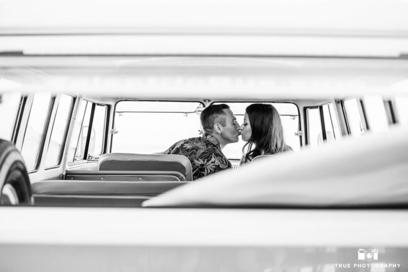 Engaged couple kiss in front seat of volkswagen bus