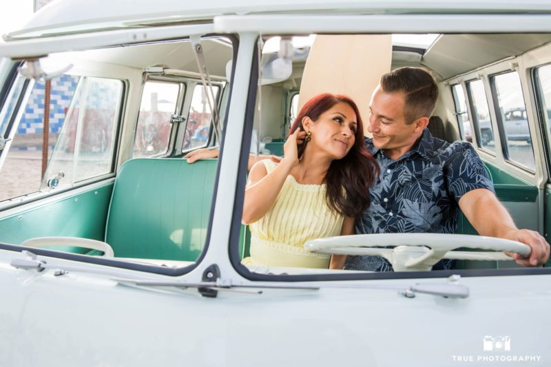 Engaged couple sit in front seat of vintage volkswagen bus