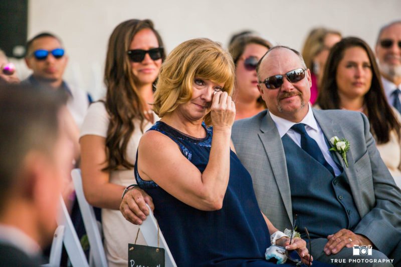 Mother of the bride wipes tears from her eyes.