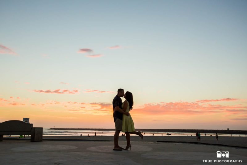 Silhouette of engaged couple kissing during sunset