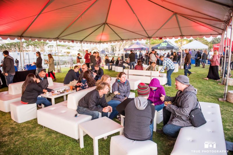 Eventgoers sit and talk under tented lounge during Best Coast Beer Fest