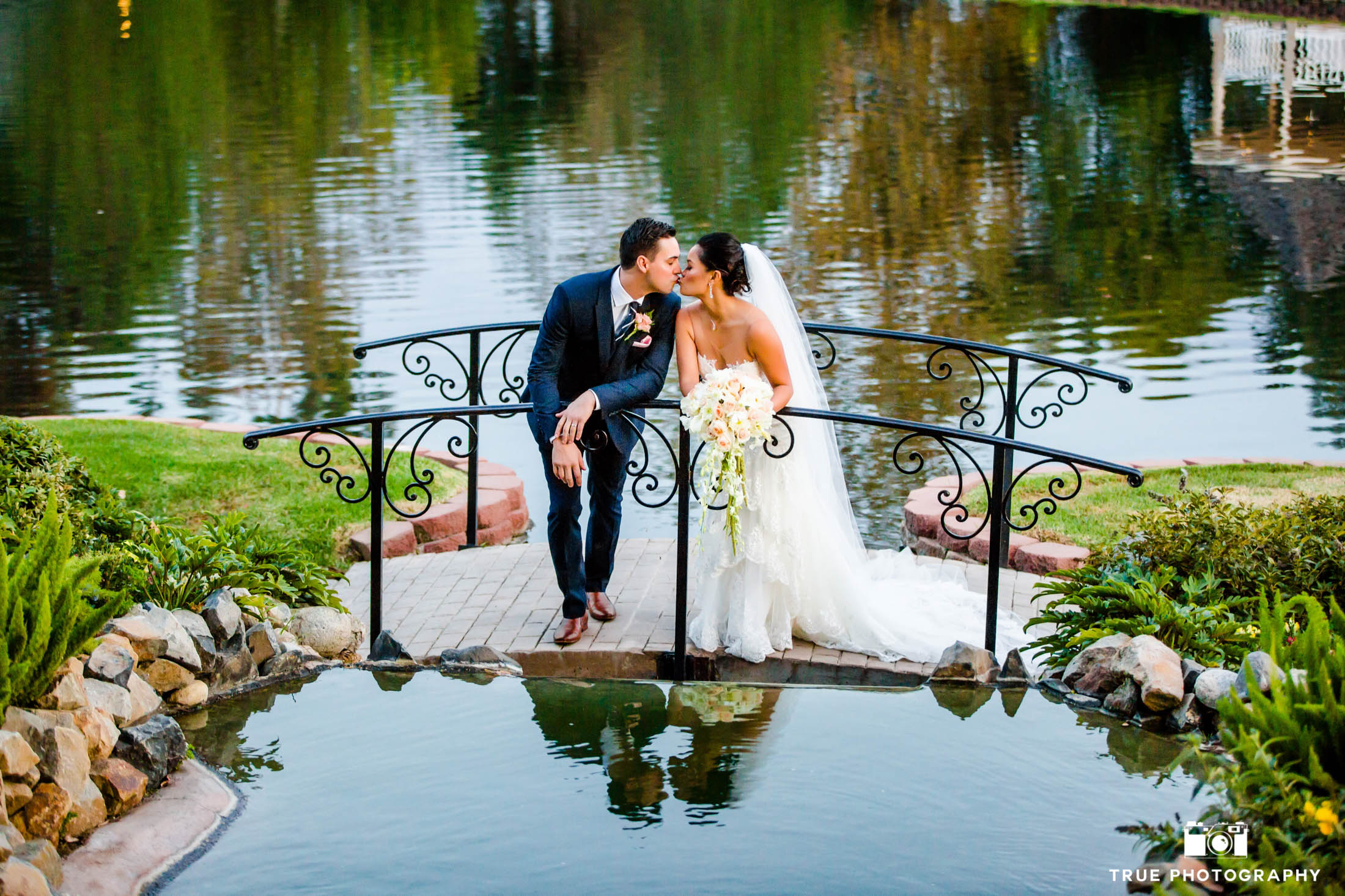 Bride and groom kissing on a bridge