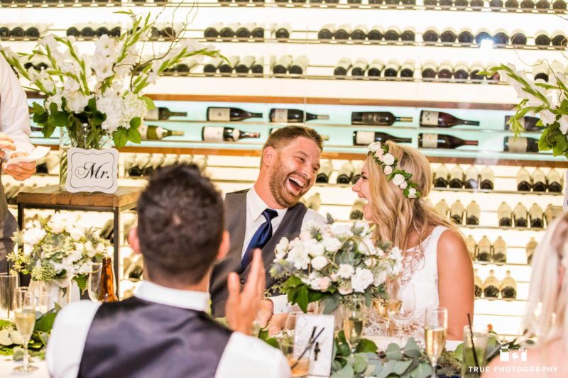 Bride and groom laugh during toasts.