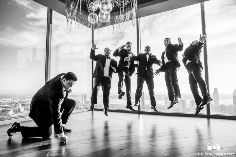 groomsmen pose for a fun jumping photo with downtown skyline in background