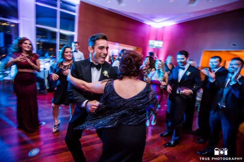 Groom dancing and laughing while dancing with guest