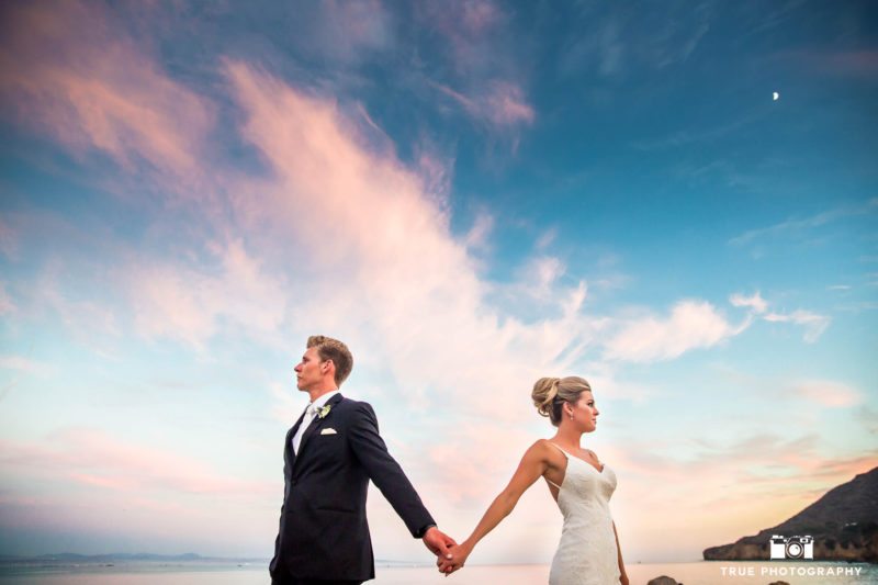 Bride and Groom hold hands during sunset after ceremony