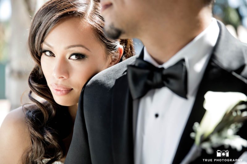 Stylish bride looks at camera over groom shoulder