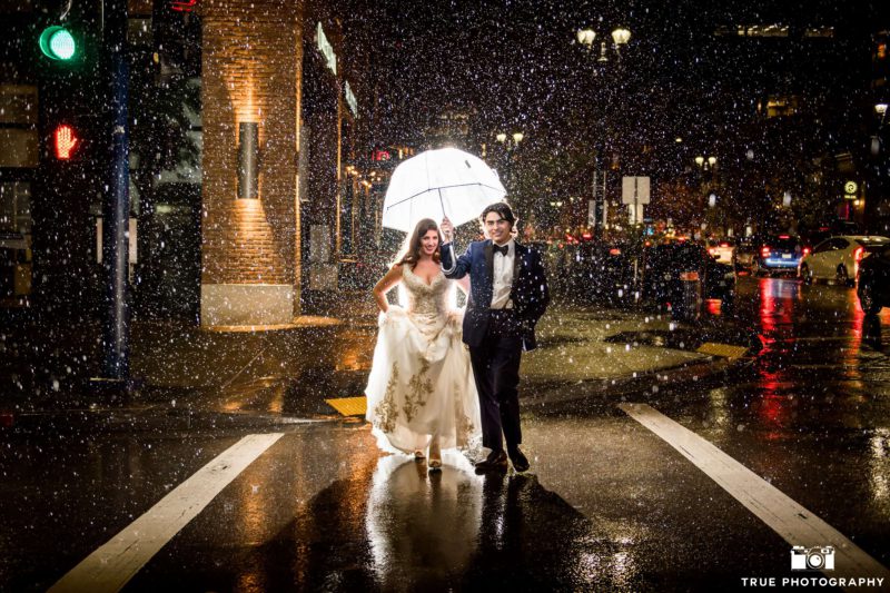 A gentleman holds an umbrella for his bride.