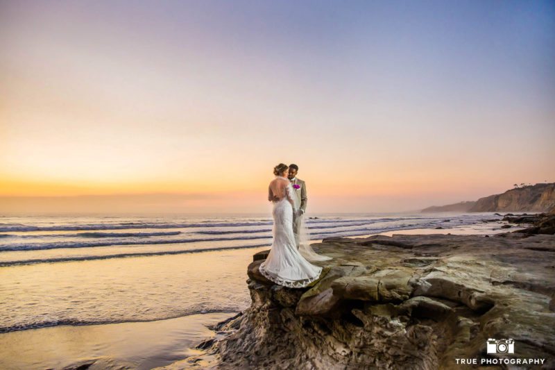 Wedding Couple embrace on cliff at Sunset