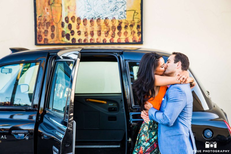 A couple kissing in front of their car