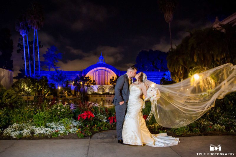 Newlyweds kiss in front of a botanical garden.