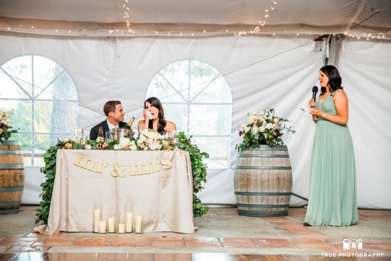 Bride and groom listen to toasts during wedding reception