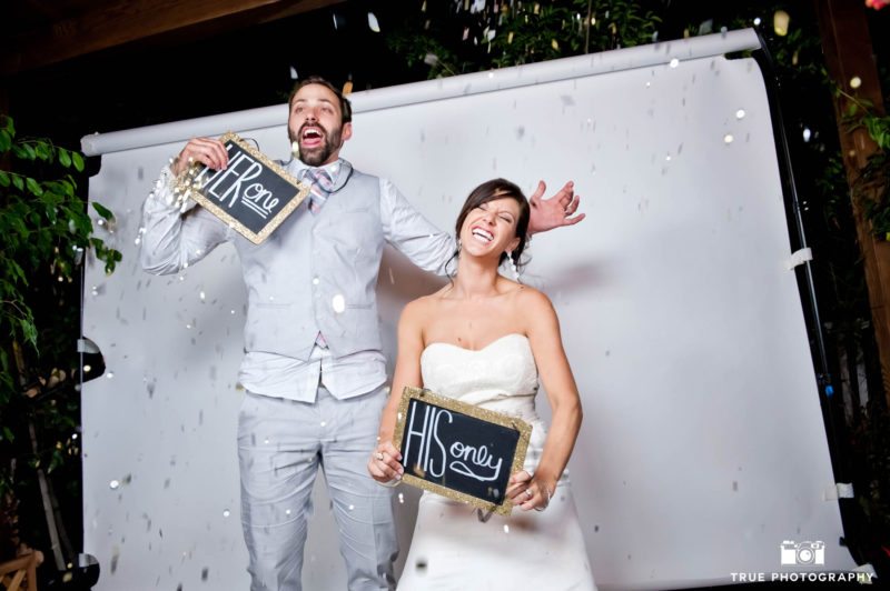 fun bride and groom pose in photobooth