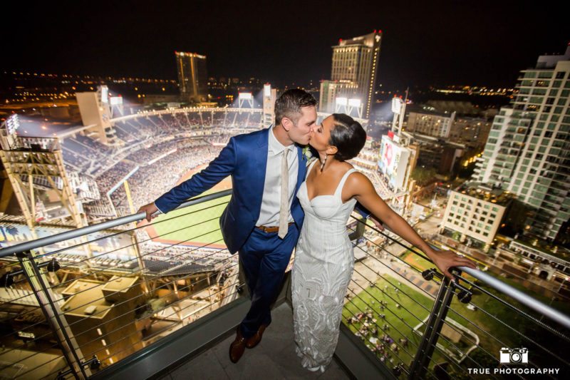 Night photo of bride and groom overlooking Petco Park and kissing