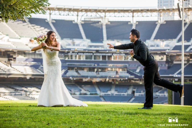 Bride and groom pretend to play baseball outside field at petco park
