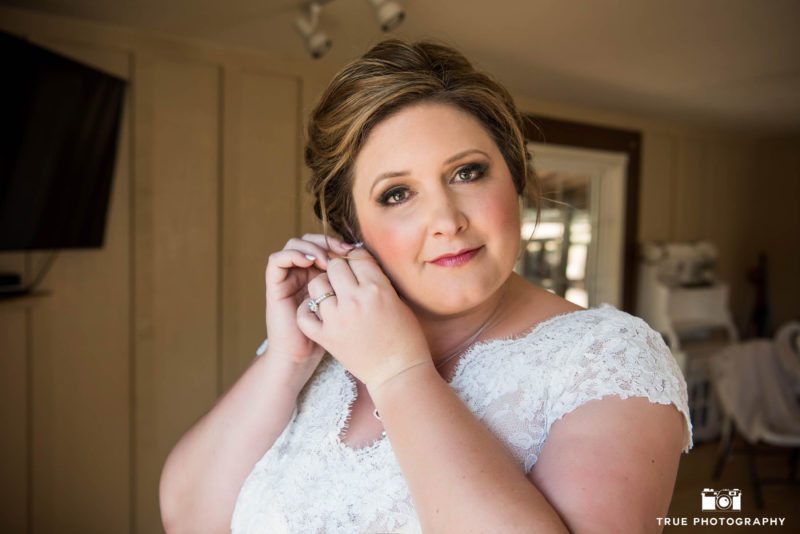 Bride putting on earrings before wedding ceremony