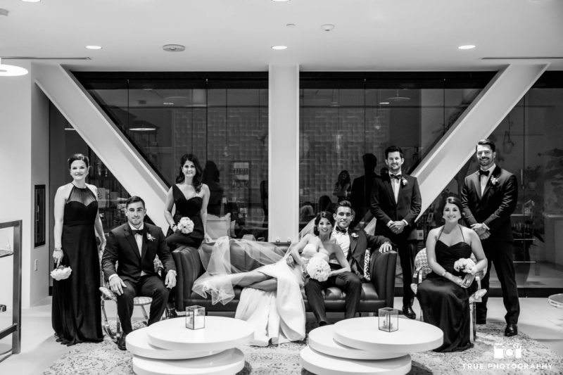 Black and white portrait of wedding couple with bridal party in lobby of ultimate skybox