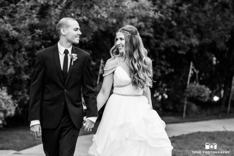 Black and white photo of bride and groom laughing and walking