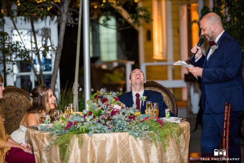 Bride and groom react with laughter during wedding toast speeches during reception
