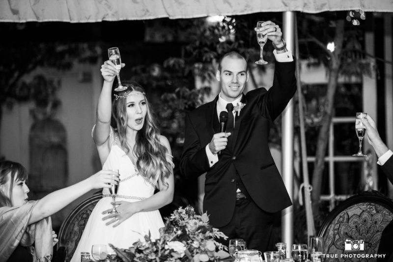 Bride and Groom raise champagne glasses and toast during their rustic wedding reception