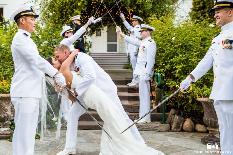 Newlyweds kiss beneath arch of swords.