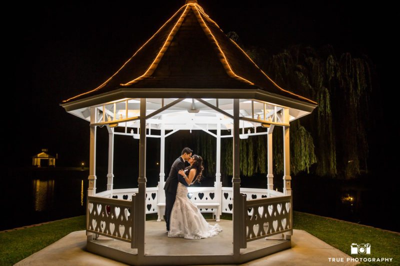 Bride and Groom kiss under white gazebo at Grand Tradition