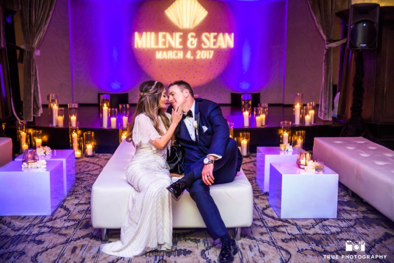 Bride and groom sit on lounge furniture during wedding reception