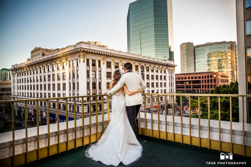 bride and groom embracing on balcony overlooking US Grant Hotel