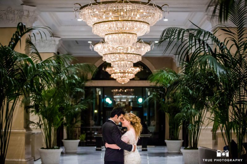 Bride and Groom embrace under luxurious chandelier at US Grant