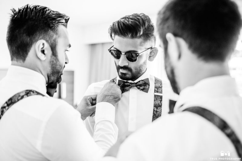 groomsmen getting ready bowtie and susperders wedding attire